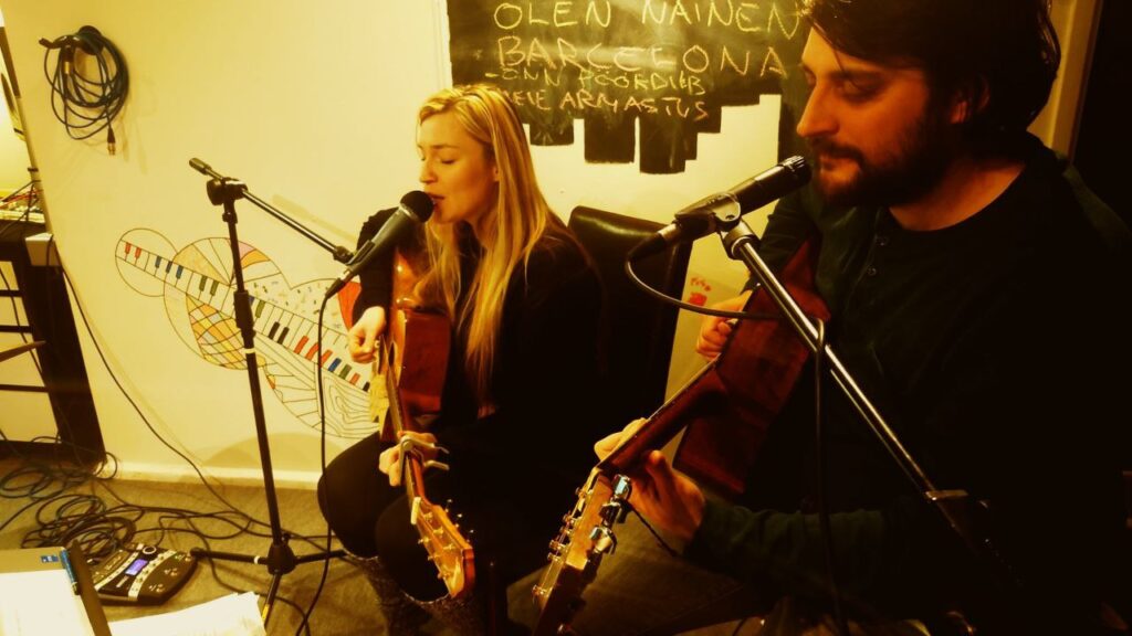 Aiki and Tuukka singing and playing guitars in rehearsal room